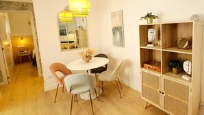 Un comedor con una mesa redonda, dos sillas, un espejo y un mueble de madera con estantes.