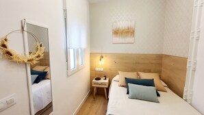 Un dormitorio con cabecera de madera, una mesita de noche con lámpara, un espejo y una guirnalda decorativa.