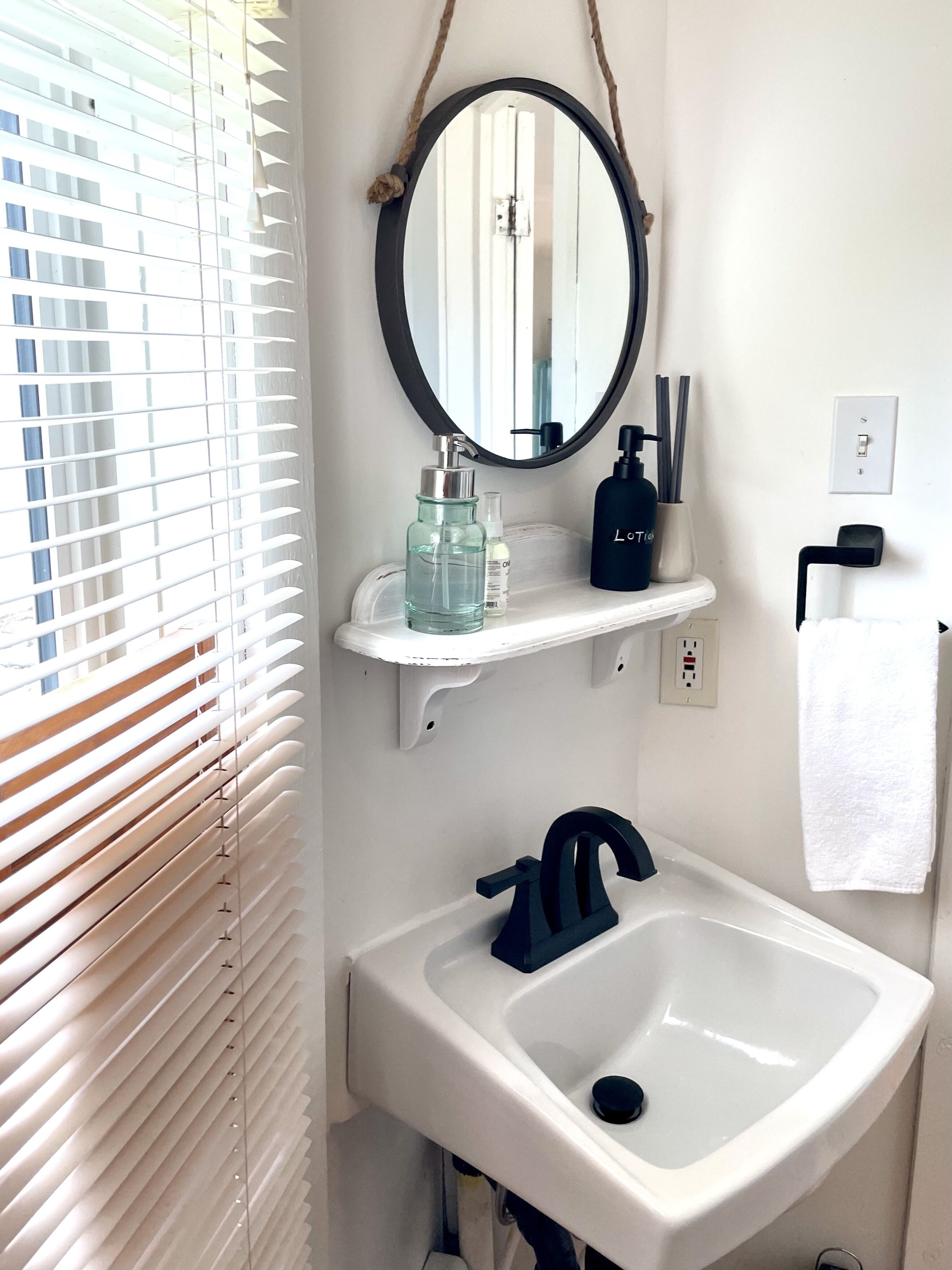 Een badkamer met een wit wastafel, een spiegel en een plank met toiletartikelen.