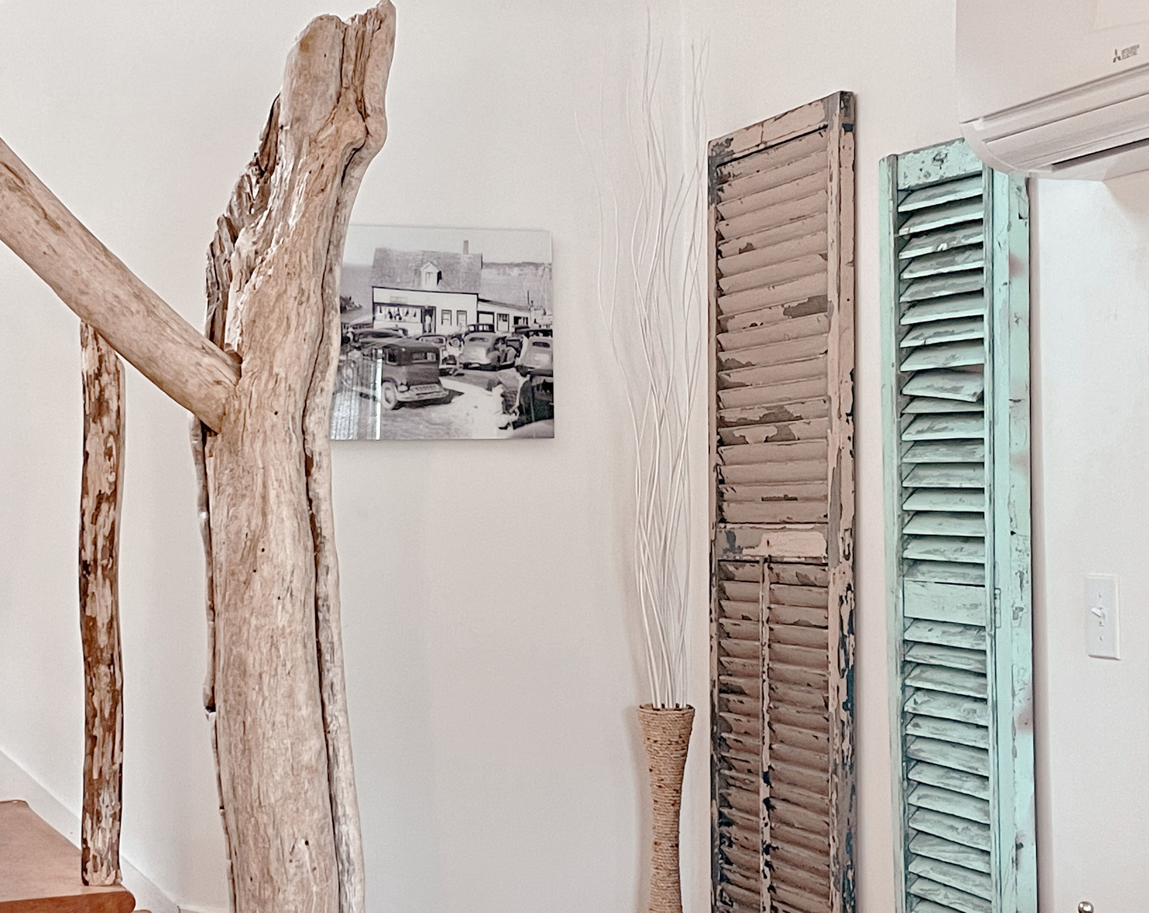 A room with a rustic wooden beam, a vintage photograph, and a door with distressed blue shutters.