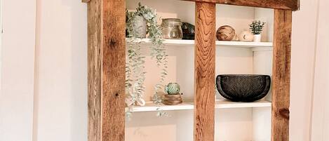 A wooden cabinet with glass doors, shelves, and baskets.