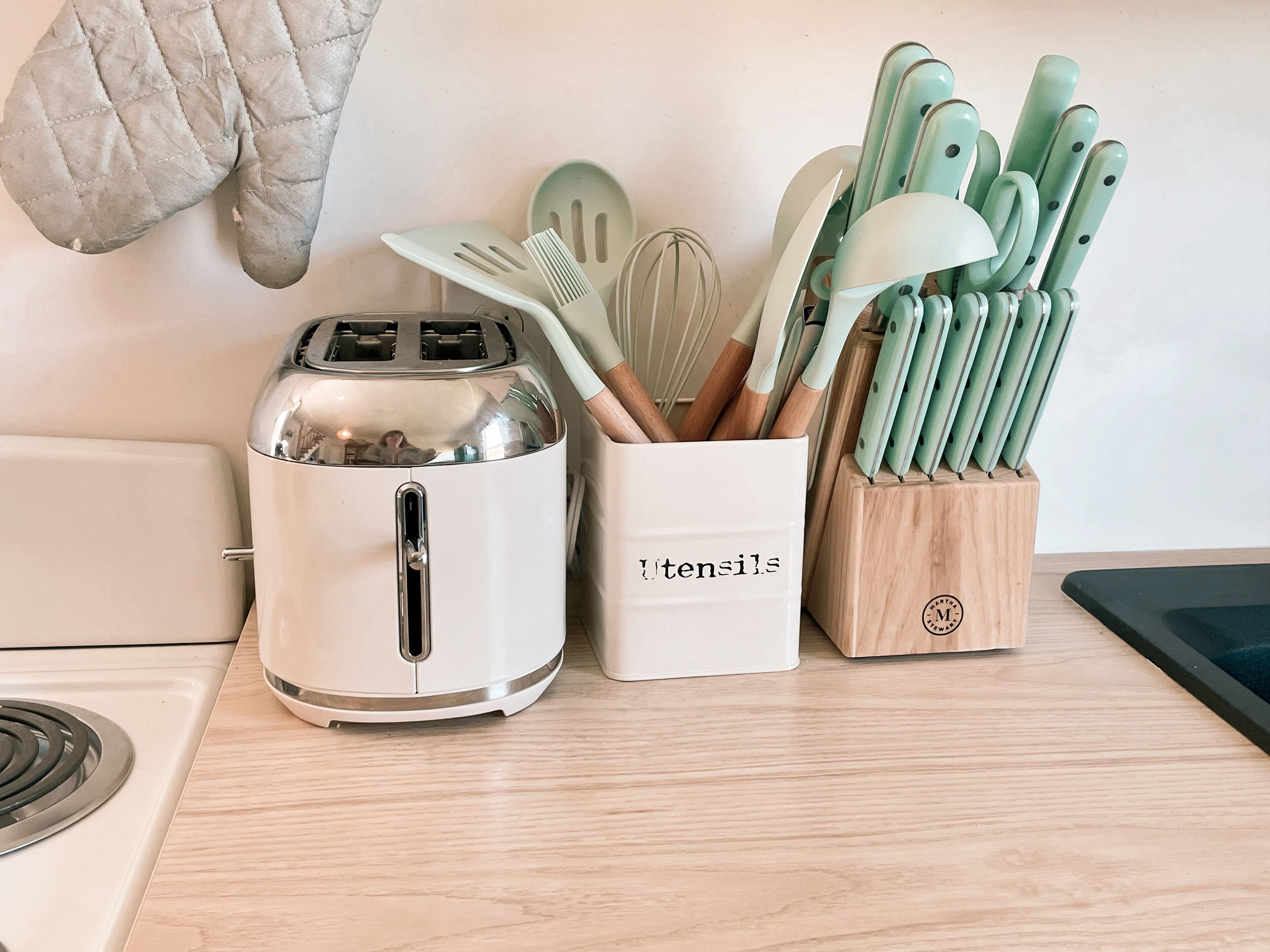 A kitchen counter with a toaster, a utensil holder, and a knife block.
