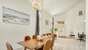 Ein Essbereich mit einem Holztisch und Stühlen, einer Chandelüster und einem Gemälde an der Wand.