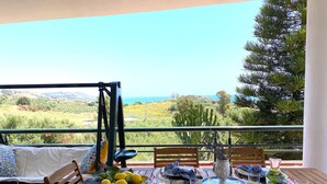 A dining table set on a balcony with a view of the sea and hills. - Holiday home with beautiful sea views, 3 minutes walk from the beach (Località Timpi Russi)