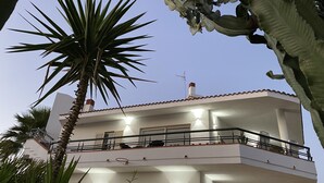 A two-story building with balconies, a visible chimney, and a well-lit exterior. - Holiday home with beautiful sea views, 3 minutes walk from the beach (Località Timpi Russi)