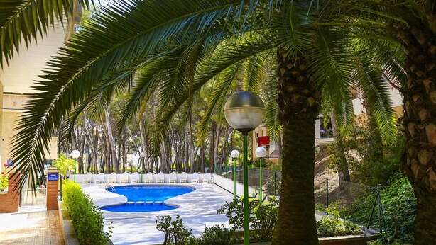 A swimming pool surrounded by palm trees and a brick wall. - 5 min to Cala Crancs | Terrace & Pool (Salou)