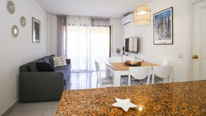 A modern apartment with a living area, a dining space, and a kitchen. - 5 min to Cala Crancs | Terrace & Pool (Salou)