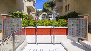 A gated entrance with a metal gate, a red brick wall, and a sign with the word "VOLAS" on the ground. - 5 min to Cala Crancs | Terrace & Pool (Salou)