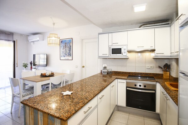 A modern kitchen with white cabinets, a granite countertop, a built-in oven, and a microwave.
