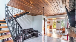 A modern interior with a wooden staircase, a leather sofa, and a kitchen area.