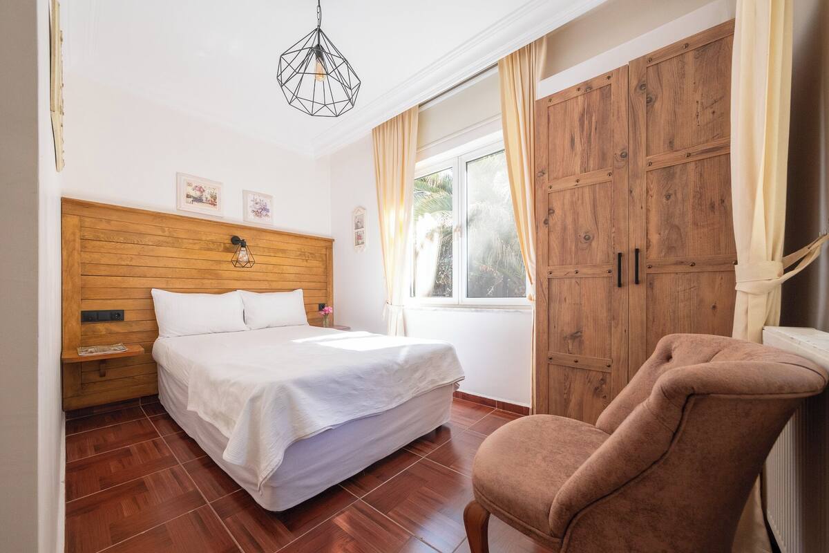 A bedroom with a wooden headboard, a bed, a chair, and a wardrobe.