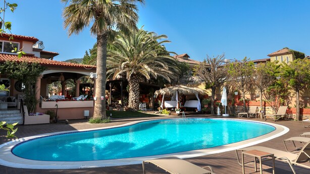 A swimming pool with lounge chairs, palm trees, and a covered seating area. - Casa Linn Boutique Hotel (Ayvacik)