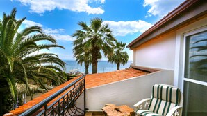 A balcony with a wooden floor, a metal railing, a striped chair, and a wooden table. - Casa Linn Boutique Hotel (Ayvacik)