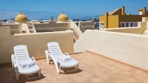 A rooftop terrace with white lounge chairs and yellow domed buildings in the background. - Home2Book Stunning Sultan Casa Estrella, Wifi (Corralejo)