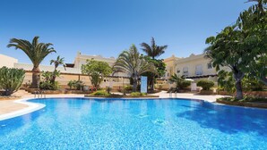 A clear blue swimming pool surrounded by palm trees and a building with a beige facade. - Home2Book Stunning Sultan Casa Estrella, Wifi (Corralejo)