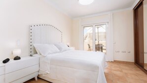 A bedroom with a bed, white nightstands, a lamp, and a view of the outside through a sliding door. - Home2Book Stunning Sultan Casa Estrella, Wifi (Corralejo)
