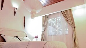 A bedroom with a bed, a bedside table, a lamp, and a window with curtains. - Secure, 2 bedroom house in a quiet neighborhood. (Nairobi County)