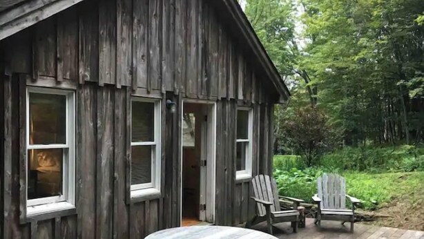 A rustic wooden cabin with a round wooden table and benches, two Adirondack chairs, and a deck. - Secure, 2 bedroom house in a quiet neighborhood. (Nairobi County)
