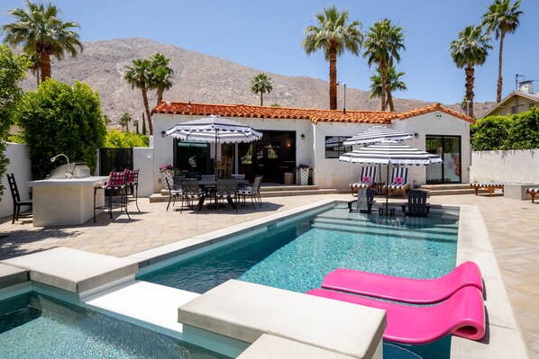 A pool area with lounge chairs, umbrellas, and a bar area. - Casa del Cielo - Walking distance to downtown Palm Springs (palm springs)
