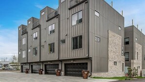 Un immeuble moderne à plusieurs étages, doté d’une façade grise, de grandes fenêtres et de plusieurs portes de garage.