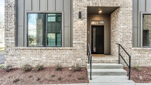 Un bâtiment moderne avec une façade en briques, de grandes fenêtres et une porte noire.