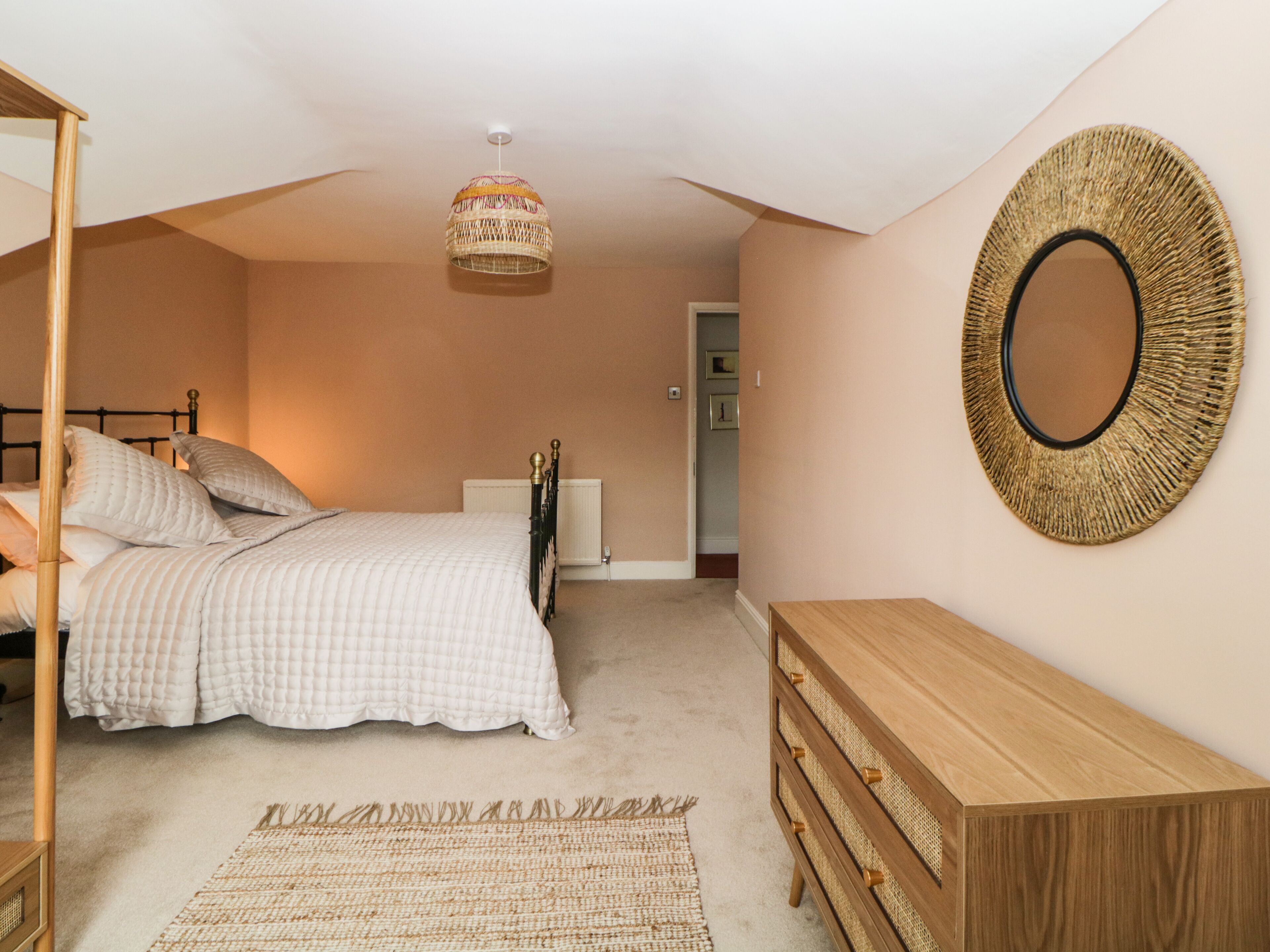 Une chambre à coucher comprenant un lit, une table de chevet, une commode et un luminaire suspendu.