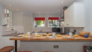 Una cocina moderna con una isla central, taburetes de bar y vistas al exterior.
