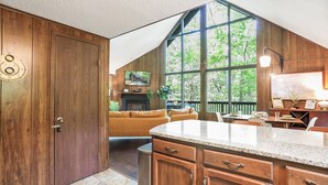 Una cocina con armarios de madera, encimera de granito y un amplio ventanal con vistas a la vegetación.