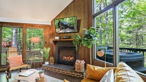 Una sala de estar acogedora con chimenea, ventanas amplias y televisor.