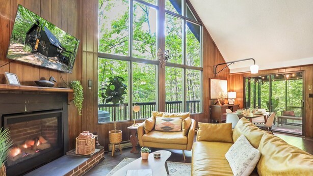 Una sala de estar acogedora con chimenea, asientos cómodos y ventanas amplias que ofrecen vistas al exterior.