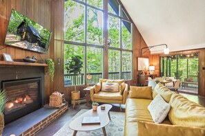 Una sala de estar acogedora con chimenea, asientos cómodos y ventanas amplias que ofrecen vistas al exterior.