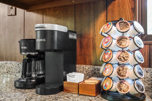 A coffee maker, a coffee pod holder, and a box labeled "TAZO" on a kitchen counter.