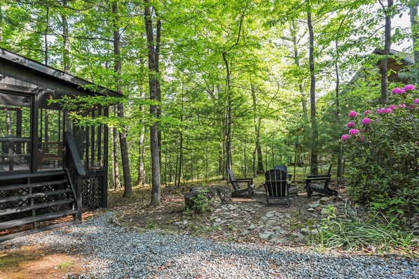 A cabin with a wooden deck and a stone pathway leading to outdoor seating.