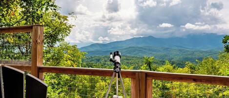Un telescopio sobre una plataforma de madera con vistas a un paisaje montañoso.