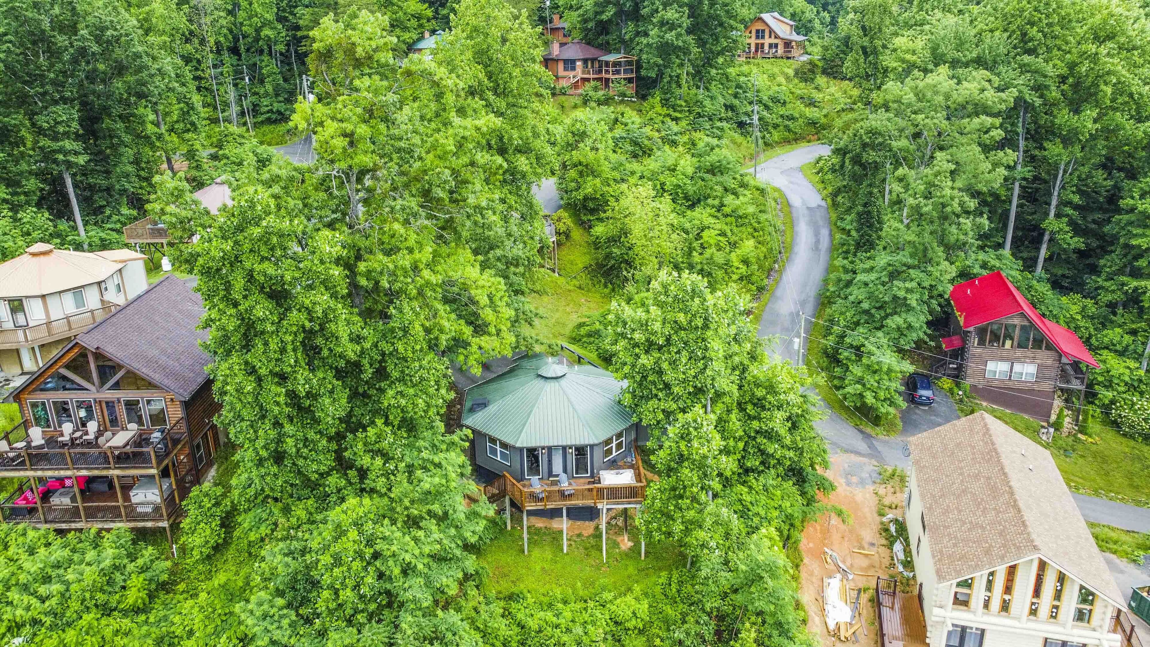 A secluded cabin surrounded by dense forest, with a winding road leading to it.
