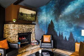 Una sala de estar acogedora con chimenea de piedra, un sillón de cuero cómodo y un mural de un cielo estrellado.