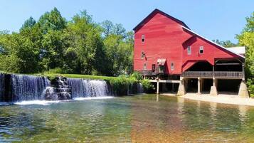 Situated near a serene waterfall, this charming barn-style building offers a peaceful retreat amidst lush green surroundings.