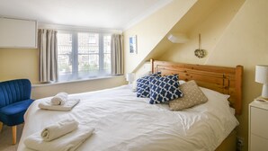 A bedroom with a bed, a chair, a window, and a ceiling light.