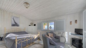 Une chambre à coucher avec un lit, un canapé, une télévision et une fenêtre avec des volets.