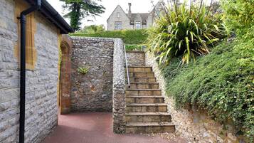 A stone staircase leading up to a building with a traditional design, surrounded by lush greenery.