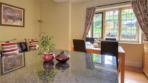 Un coin repas avec une table en granit, deux plantes en pot et une fenêtre avec des rideaux.