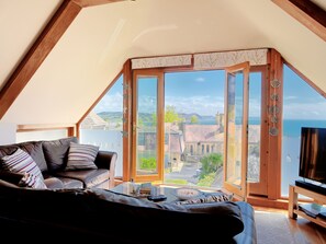A cozy room with a large window, a sofa, and a television. - Bucket & Spade (Lyme Regis)
