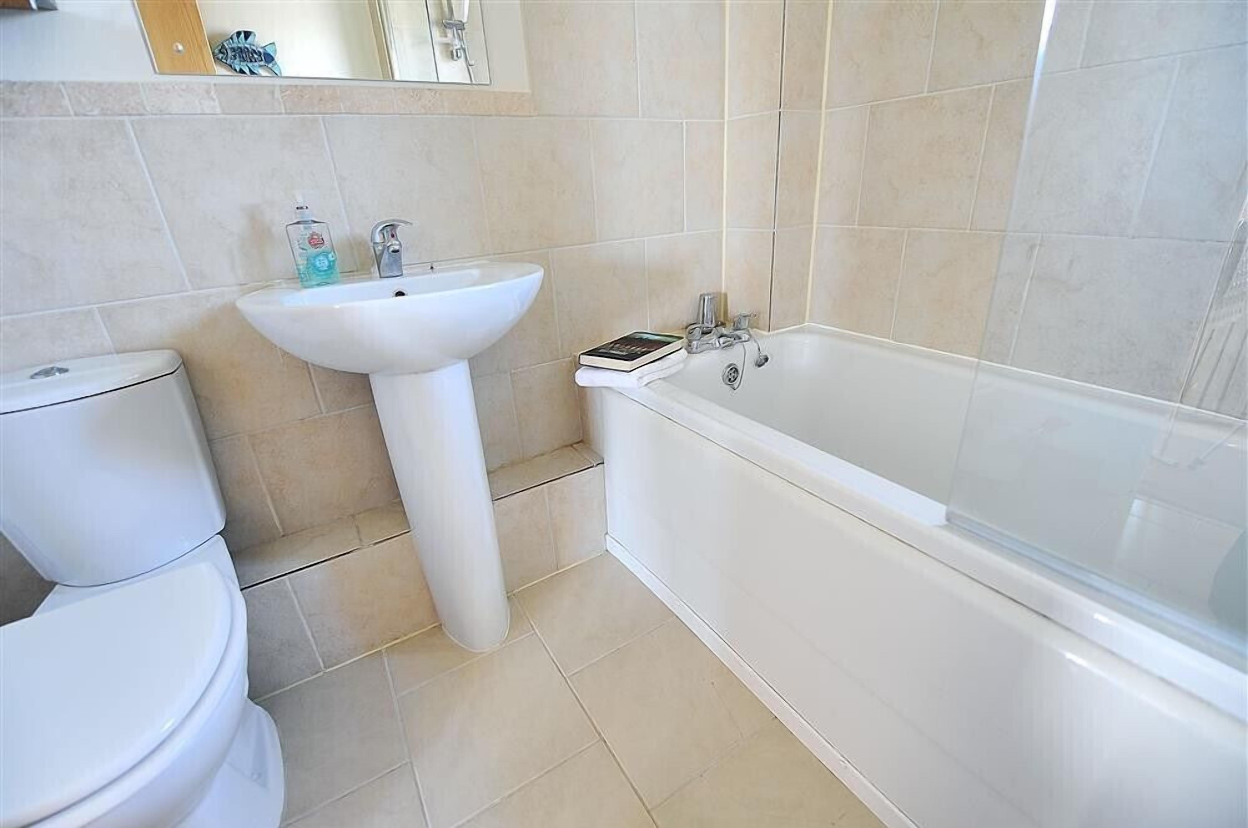 Een badkamer met toilet, wastafel en bad.