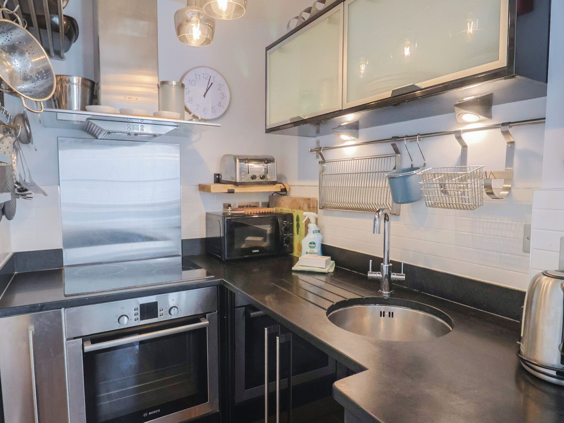 A modern kitchen with stainless steel appliances, a built-in oven, a toaster, and a sink.