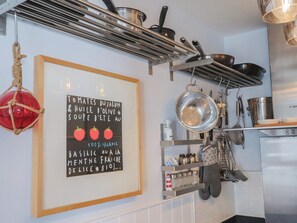 Une cuisine avec des casseroles suspendues, un panneau décoratif encadré et divers ustensiles.
