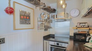 Une cuisine équipée d’appareils électroménagers en acier inoxydable, d’un four Bosch, d’un four à micro-ondes et d’ustensiles de cuisine suspendus.