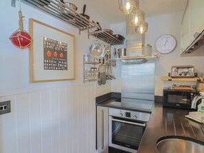 A kitchen with stainless steel appliances, a Bosch oven, a microwave, and hanging utensils. - Seaside (Lyme Regis)