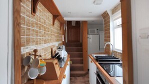 A narrow kitchen with a wooden counter, a built-in stove, and a microwave. - Windwhistle (Lyme Regis)