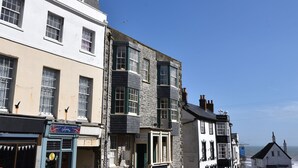 A row of buildings with various storefronts, including a shop with a blue awning and a sign that reads "Royal Lion." - Okanagan (Lyme Regis)