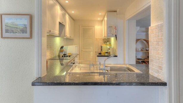 A narrow kitchen with a sink, cabinets, and a countertop. - Okanagan (Lyme Regis)